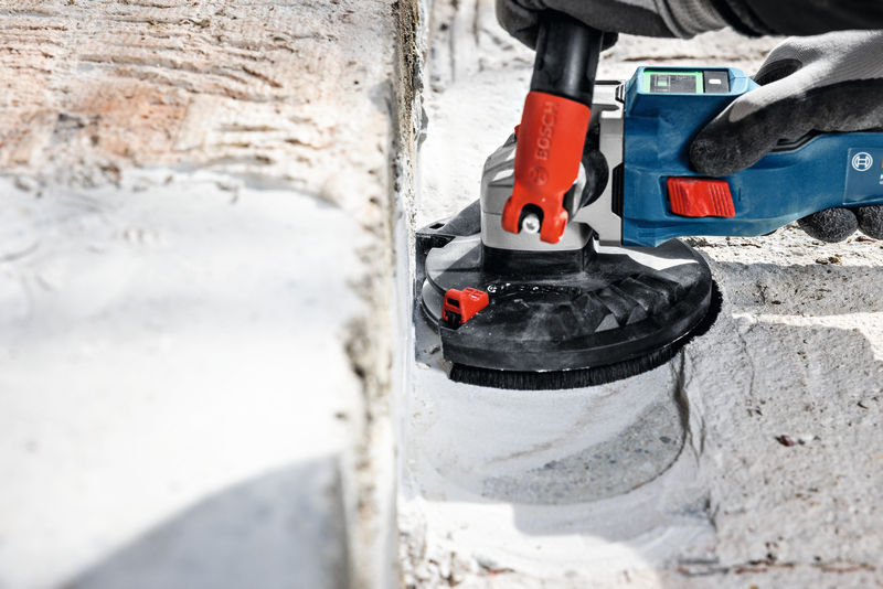 Eine Person mit Sicherheitsausrüstung schleift Beton mit einem blauen Elektrowerkzeug. Anwendungsbild