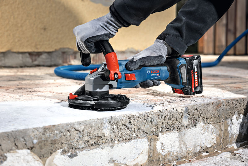 Eine Person mit Schutzausrüstung glättet Beton mit einem Akku-Schleifgerät. Anwendungsbild